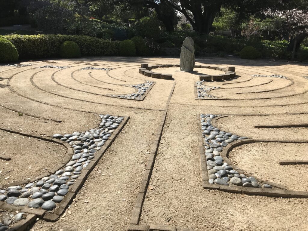 Picture of an outdoor garden with circles on the ground with a statue in the middle