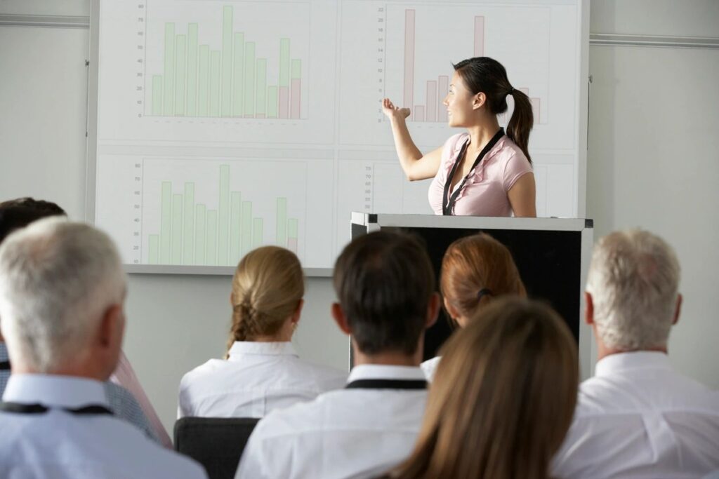 Image of a woman talking in front of a crowd on the leadership development page. 